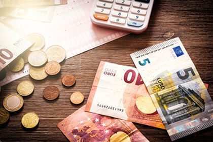 ein Haufen Geld in Scheinen und Münzen und ein Taschenrechner