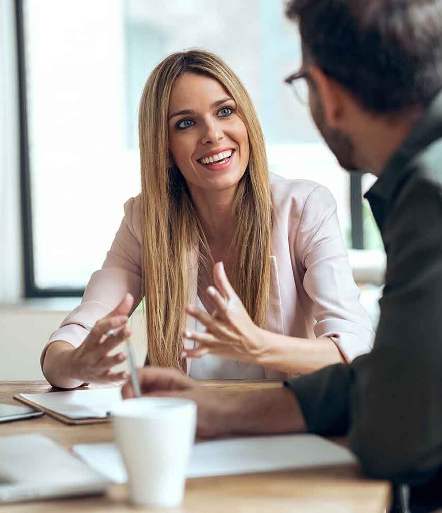 eine Frau und ein Mann, die an einem Tisch sitzen und reden